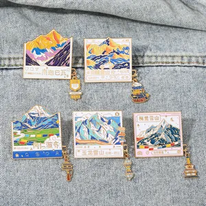 Détail de cinq badges émaillés illustrant des montagnes enneigées et charms culturels