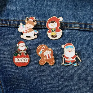 Detailed view of five Christmas enamel pins including Santa and snowman on denim fabric