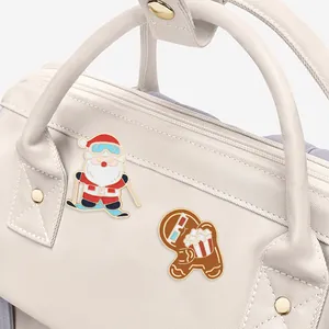 Detailed enamel pins of skiing Santa and gingerbread man pinned on a beige nylon bag