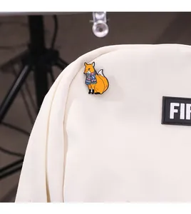 Primer plano detallado de un pin esmaltado de zorro animado en una mochila de lona blanca