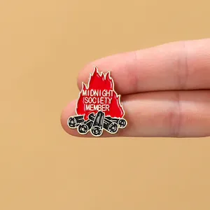 Close-up of Midnight Society Member campfire enamel pin held to show actual size