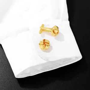Detail of gold twisted knot cufflinks on a white shirt cuff with a matte black background