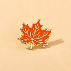 Détail de la broche émaillée en feuille d'érable orange avec nervures dorées brillantes
