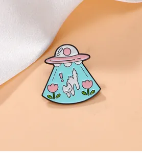 Détail macro d'une broche chat OVNI en émail avec tulipes roses sur un tissu en soie
