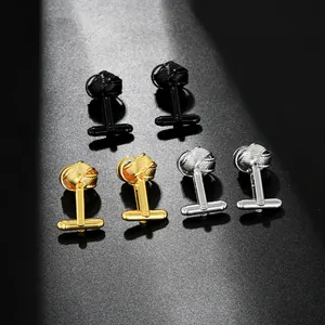 Detailed view of metal knot cufflinks in black, gold, and silver on a textured surface