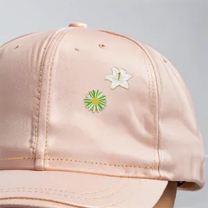 Schicke Emaille-Anstecknadeln mit Lilien- und Gänseblümchenmotiven auf einer rosa Kappe