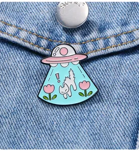 Détail d'une broche émaillée chat OVNI épinglée sur la poche d'une veste en jean