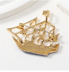 Detailed back view of golden sailboat brooch showing safety pin clasp and metal texture