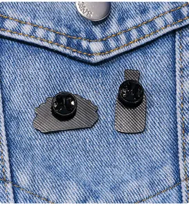 Makro-Detail von Emaille-Pin-Rückseiten mit rutschfester Textur auf Denim-Jacke