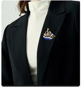 Detail of creative sailboat brooch with blue enamel on a black suit lapel