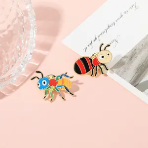 Detailed view of colorful ant and bee enamel pins on a soft pink decorative background