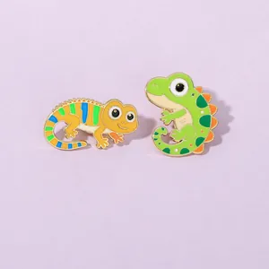 Close-up of two cute lizard enamel pins in green and yellow with vibrant details