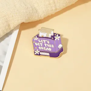 Close-up of a purple toaster enamel pin featuring the phrase Let's Get This Bread
