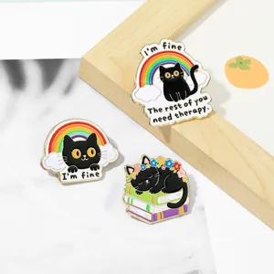 Detail of three black cat enamel pins with motivational quotes on a clean desk