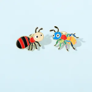 Close-up of cute colorful ant and striped insect enamel pins on a blue surface