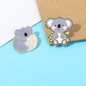 Dettaglio di spille in metallo a forma di koala con bordi dorati e finitura smaltata