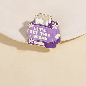 Macro shot of purple toaster enamel pin with Let's Get This Bread text and daisy flowers