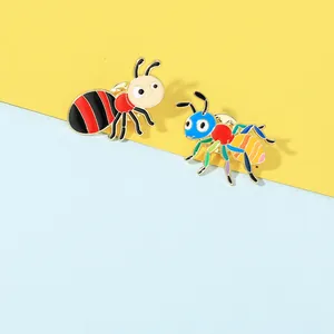 Detail of two colorful cartoon ant enamel pins featuring polished gold finish and bright colors