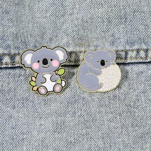 Dettaglio di spille koala in smalto su denim blu che mostra i bordi in metallo dorato