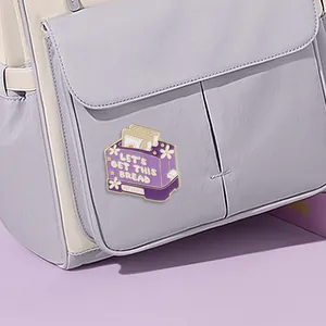 Purple toaster enamel pin Let's Get This Bread badge on a backpack pocket