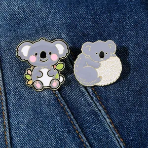 Dettaglio di spille in smalto con koala su denim, mostra la fattura in lega metallica