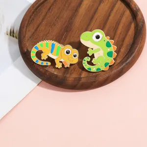 Detail of colorful lizard enamel pins with vibrant drip oil finish on a wooden tray