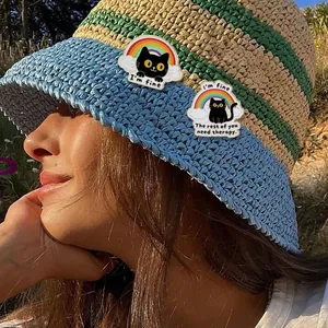 Cute black cat enamel pins with rainbow clouds and humorous quotes on a straw hat