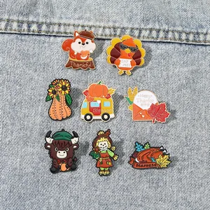 Set of eight Thanksgiving enamel pins including turkeys and pumpkins on denim fabric