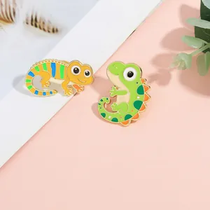 Detail of colorful enamel lizard and dinosaur animal brooches with gold metal edges