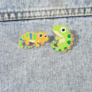 Detailed shot of two colorful lizard enamel pins on a blue denim jacket background