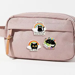 Three-piece black cat enamel pin set with humorous quotes pinned on a fabric bag