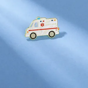Detail shot of a cartoon ambulance enamel pin with red Star of Life and golden edges