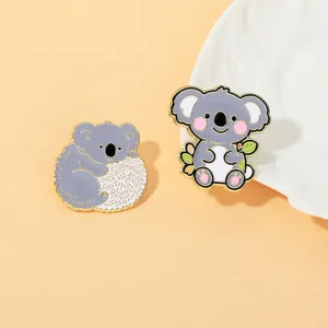 Dettaglio di due graziose spille smaltate a forma di koala con bordi dorati