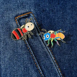 Detailed close-up of cartoon ant enamel pins pinned on blue denim fabric background