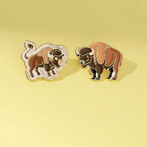 Detailed view of two bison enamel pins with golden metal edges on a light background