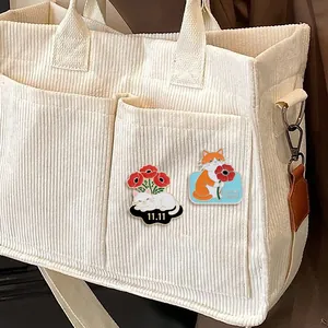 Broches en émail chat et coquelicot sur un sac en velours blanc pour souvenir