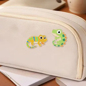 Cartoon enamel gecko and reptile pins set on a minimalist canvas zipper pouch