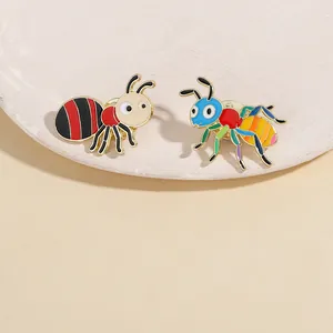 Detail of colorful cartoon ant enamel brooches on a textured marble display