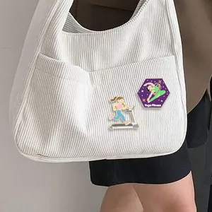 Détail de broches émaillées yoga et course fixées sur une poche de sac en velours côtelé
