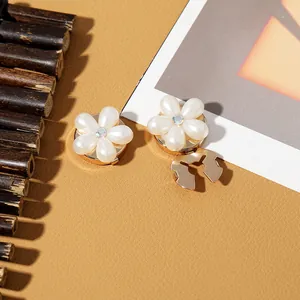 Detailed close-up of pearl flower brooch clips with rhinestone centers on leather texture