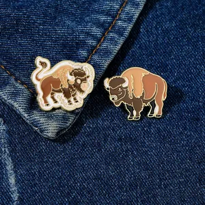 Detailed view of two cartoon yak enamel pins pinned on blue denim fabric background