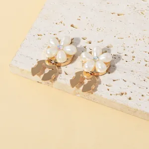 Detail of floral earrings with white pearls and gold metal drop on a stone base