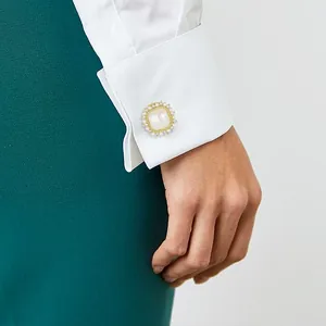 Square gold cufflink with white pearl and sparkling crystals on a white shirt cuff