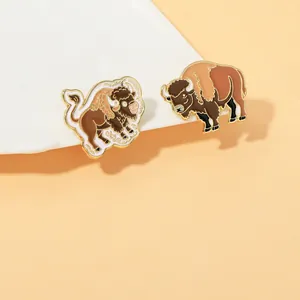 Detail of two creative bison enamel pins with natural brown tones and gold metal edges