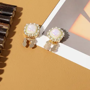 Detail of square gold earrings with lavender luster centers and pearl crystal borders