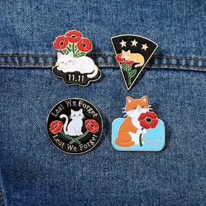 Détail de quatre épinglettes chat en émail avec coquelicots rouges sur fond en jean