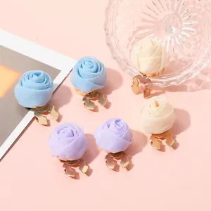 Nahaufnahme der Rosenblüten-Clips aus Seide in Blau, Lila und Creme auf Goldbasis