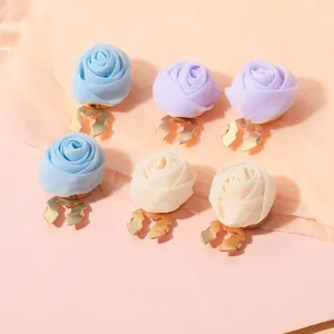 Detail von handgefertigten Stoffrosen-Ohrclips in Pastellblau, Violett und Cremeweiß