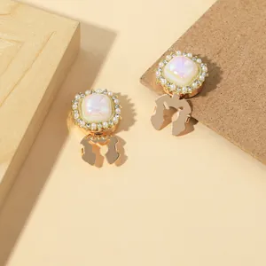 Detailed close-up of gold shirt collar buttons with white stones and pearl accents