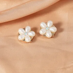 Detailed close-up of elegant flower pins with pearl petals and rhinestones on satin fabric